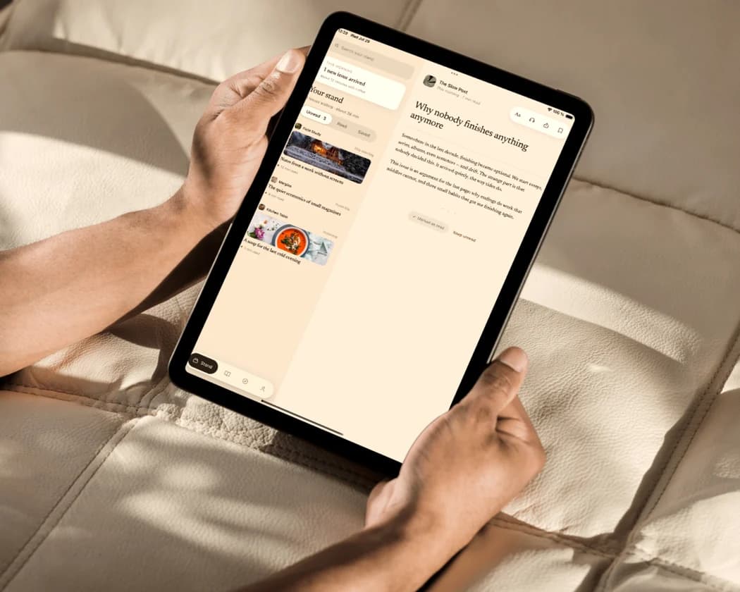 Someone holding a tablet on a sofa, reading their stand