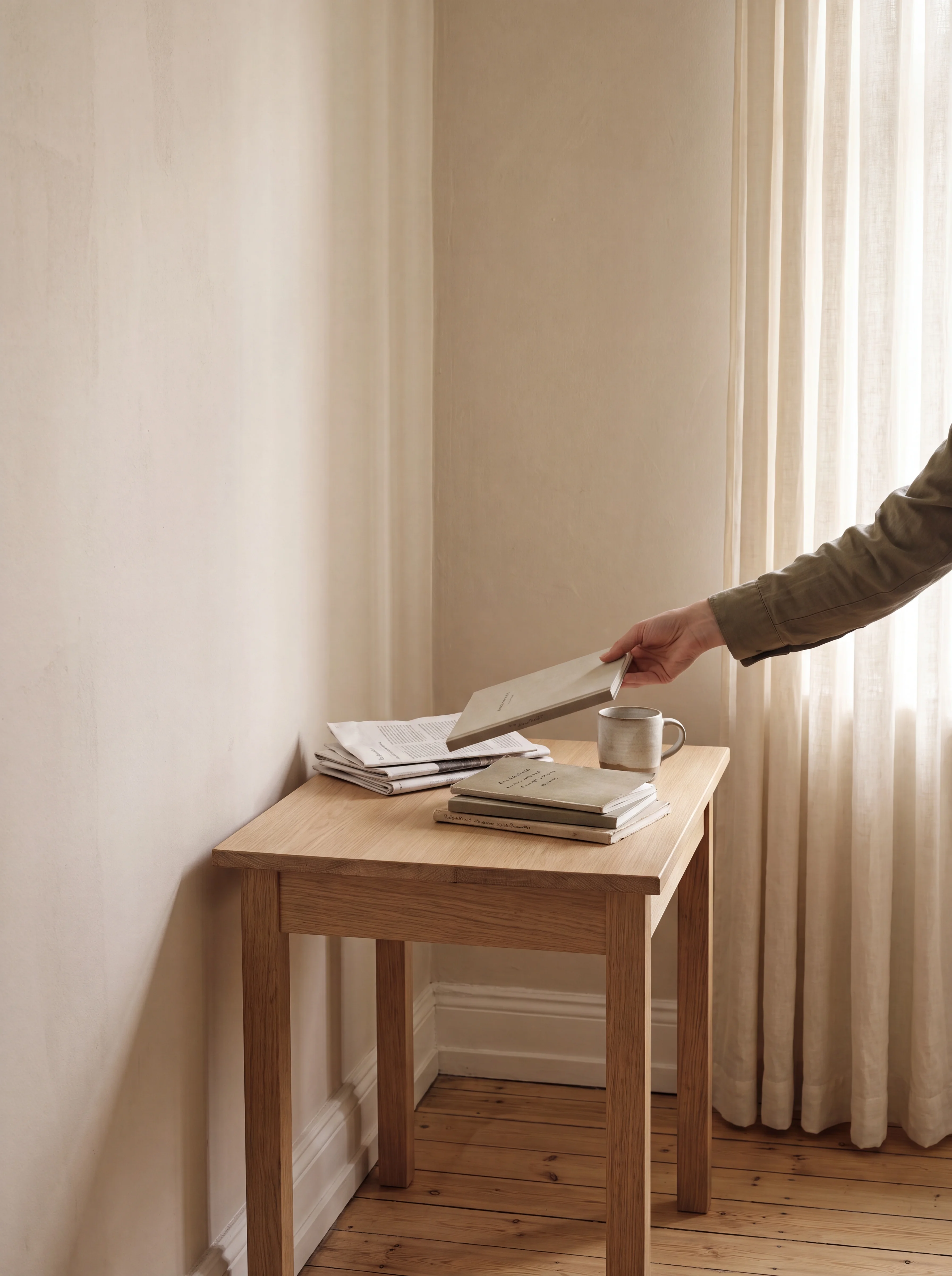 A sunlit reading nook — a hand reaching for a stack of printed journals